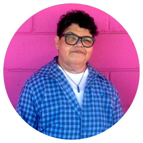 This is a headshot image of a woman posing in front of a pink brick wall.