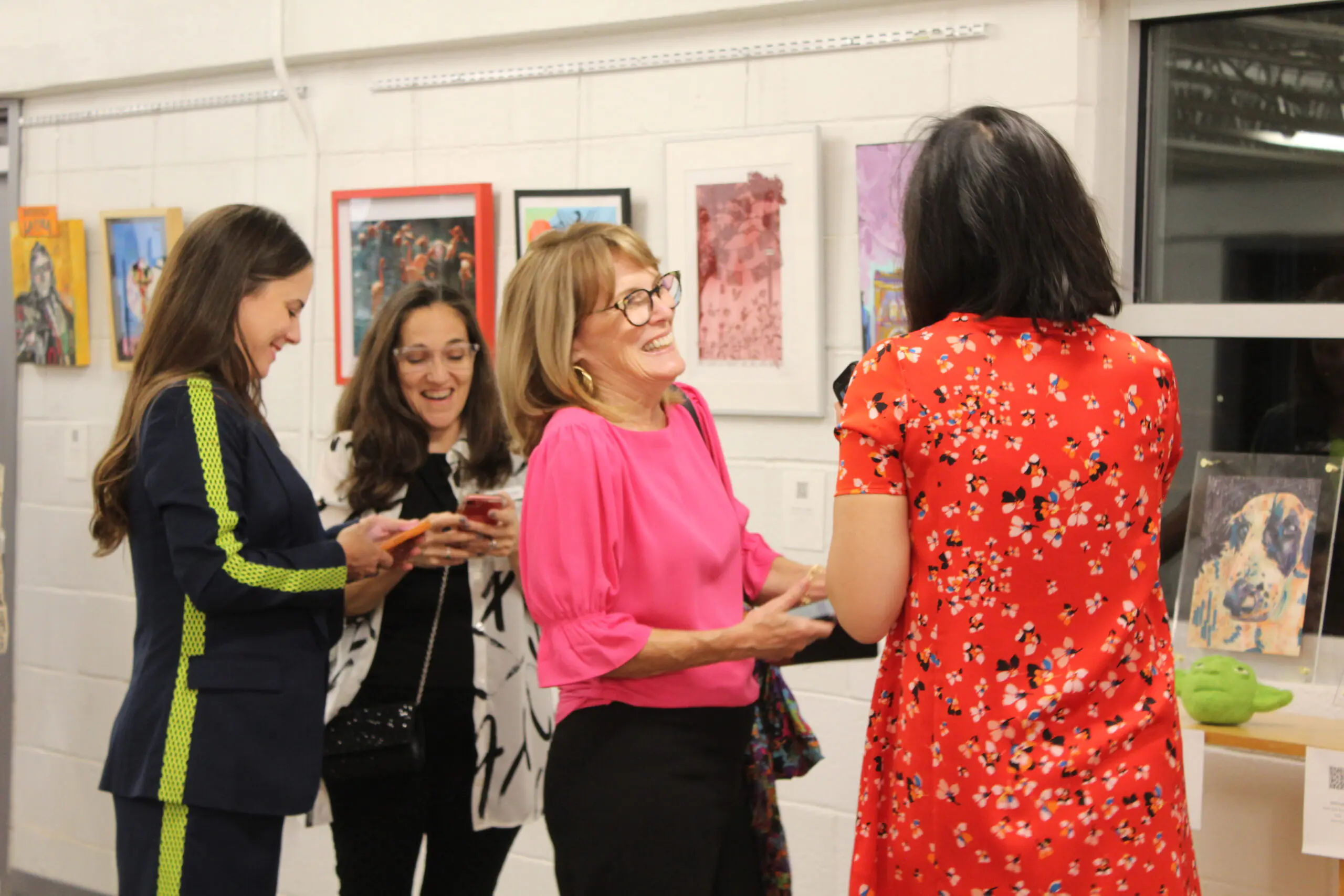 This is an image of a group of women in an art gallery. They are laughing and smiling.