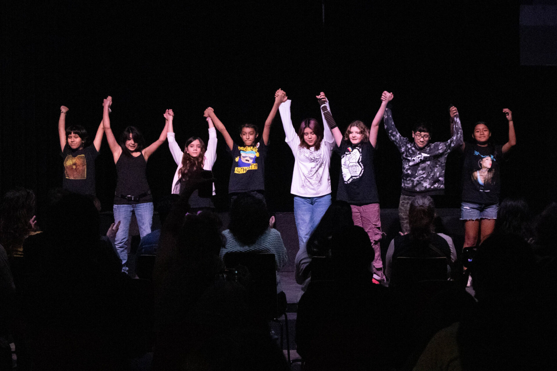 This is an image of students on stage. They are holding hands and getting ready to bow together after a theater performance.